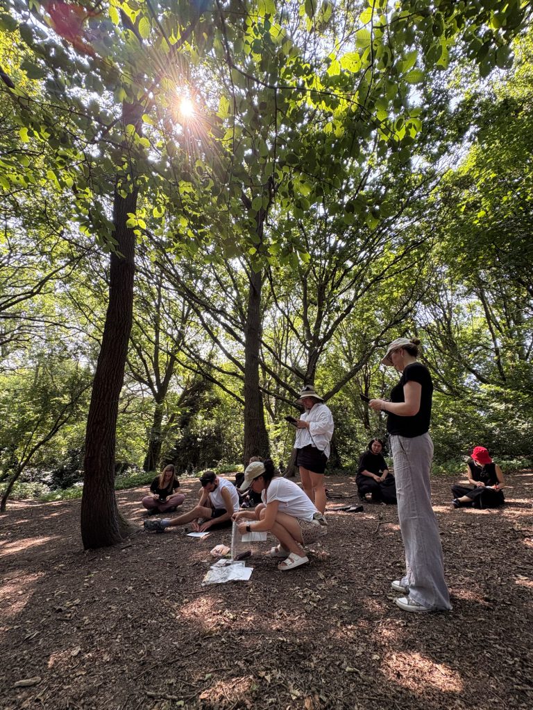 Group gathered under dappled sunlight in the woods, creating drawings inspired by the Parliament Hill Viewpoint.